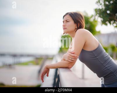 asian giovane forte, donna fiduciosa in abiti sportivi sensazione di male in procinto di buttare in su. Disidratazione. Dolore toracico. Cucitura laterale, crampi laterali dopo il funzionamento. Mal di stomaco dopo il jogging. Foto Stock