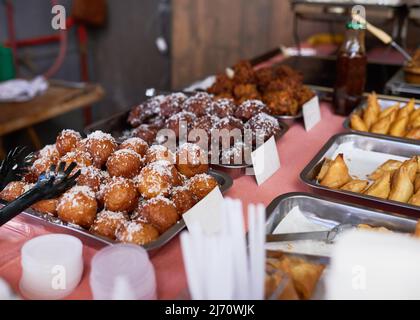 Palle di koeksuore spolte in cocco sono in vendita in un mercato sudafricano Foto Stock