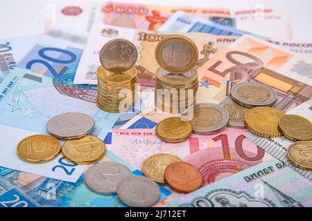 Una pila di monete rubli e monete in euro sullo sfondo della carta moneta, primo piano Foto Stock