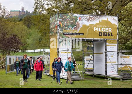 05 maggio 2022, Turingia, Eisenach: I pellegrini camminano lungo la 'Bibbia del Pellegrino' ai piedi del Castello di Wartburg all'inizio del relay di pellegrinaggio da Eisenach a Wittenberg per celebrare l'anniversario di '500 anni di traduzione della Bibbia'. L'arrivo dei pellegrini a Wittenberg è previsto per il 19 maggio 2022. Foto: Michael Reichel/dpa Foto Stock