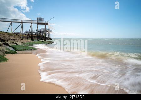 Capanne di pesca sulla costa atlantica con onde oceaniche sulla spiaggia di sabbia nella Charente-Maritime, Francia vicino alla foce della Gironda Foto Stock