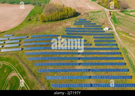 Pannelli solari su una collina sovrastati di verde, illuminati dalla luce del sole. Vista dal drone. Foto Stock