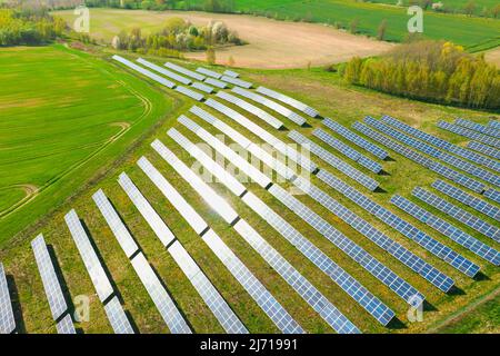 Pannelli solari su una collina sovrastati di verde, illuminati dalla luce del sole. Vista dal drone. Foto Stock