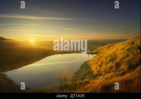 Piccolo lago e colline ondulate al tramonto. Paesaggio in Crete Senesi, Asciano, Toscana, Italia Foto Stock
