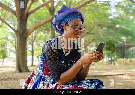 bella donna africana all'aperto gioco con il cellulare Foto Stock