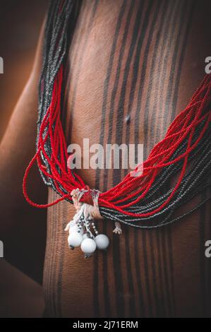 Primo piano della parte posteriore di un uomo indiano guerriero che indossa gioielli perle e vernice tribale corpo. Uomo tribù Asurini, Amazzonia brasiliana. 2007. Foto Stock