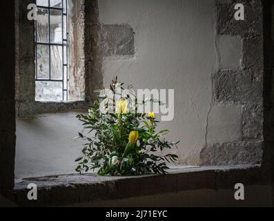 Fiori nella cavità della finestra presso la chiesa di All Saints, East Meon, Hampshire. Foto Stock