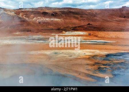 Vapore da fumarole, escursionisti in rosso-arancio paesaggio vulcanico, cresta Namafjall, Hveraroend zona geotermica, anche Hverir o Namaskard, Myvatn Foto Stock