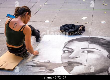 Pittore di strada andaluso femminile che dipinge un ritratto della donna su un marciapiede in un'area pedonale, Siviglia, Andalusia, Spagna Foto Stock