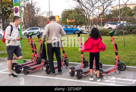 Famiglia - l'uomo, il ragazzo giovane e la ragazza stanno prendendo voi spagnolo scooters pubblici condivisi per usare nella via di Siviglia, Andalucia, Spagna Foto Stock