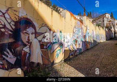 Murale raffigurante ragazza donna sul muro in strette stradine di ciottoli di Barrio Realejo, Granada, Andalusia, Spagna Foto Stock