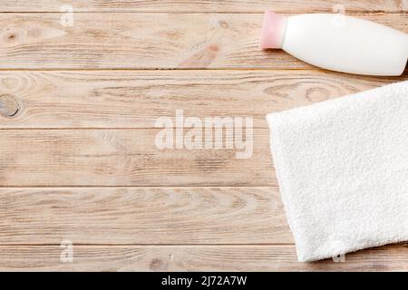 Boccetta per shampoo cosmetico con asciugamani su un tavolo colorato. Sfondo bagno, accessori per la cura delle mani e del corpo. Foto Stock