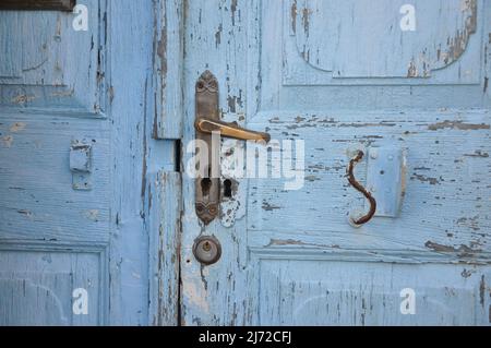 Una vecchia serratura della portiera arrugginita, maniglia della portiera anteriore. Dettaglio porta in legno intemperie blu. Foto Stock