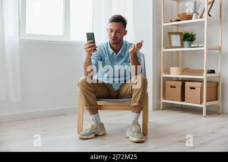 Self-fiducioso felice allegro parlare del suo business al pubblico attraente giovane uomo guarda schermo tenere telefono registrare video revisione a casa. Nuovo Foto Stock