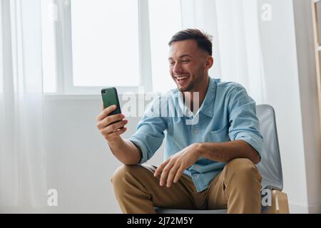 Felice carino gioioso parlare con un amico utilizzando telefono videochiamata discute le ultime notizie piacevole sollevare sorrisi guarda lo schermo. Comunicazione a distanza Foto Stock