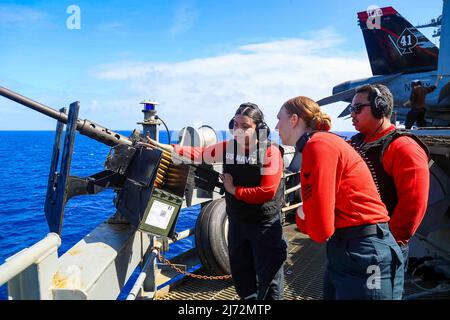 28 aprile 2022 - Philippine Sea - Aviation Ordnanceman 1st Class Holly Wilkinson, middle, from Carson City, Never., istruisce Aviation Ordnanceman 3rd Class Kennedy Lunavasquez, da Los Angeles, sul caricamento delle munizioni in una mitragliatrice di calibro .50 durante un esercizio di fuoco a bordo della portaerei di classe Nimitz USS Abraham Lincoln (CVN 72). Il gruppo Abraham Lincoln Carrier Strike è in fase di implementazione nell'area delle operazioni della flotta USA 7th per migliorare l'interoperabilità attraverso alleanze e partnership, fungendo da forza di risposta pronta a sostenere un libero e aperto Indo-Pacifi Foto Stock