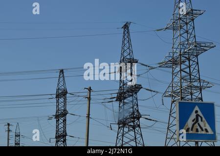 Le torri di trasmissione ad alta tensione, dove molti fili, hanno uno sfondo cielo chiaro. Vista delle torri elettriche. Colonna di fili ad alta tensione contro il blu Foto Stock