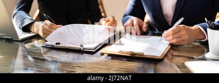 Due colleghi di lavoro seduto alla scrivania lavorando insieme in ufficio Foto Stock