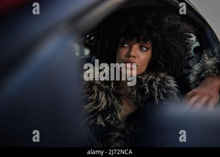 Donna afroamericana seduta in auto in attesa al semaforo di notte. Foto Stock