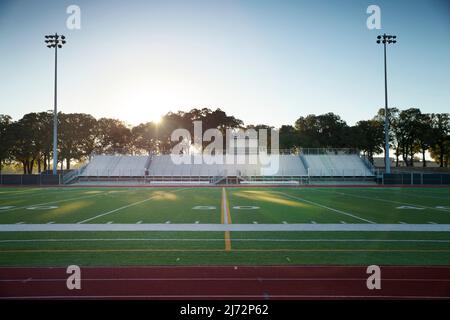 Vista a livello del campo di una pista delle scuole superiori e di un campo da calcio in Texas all'alba Foto Stock