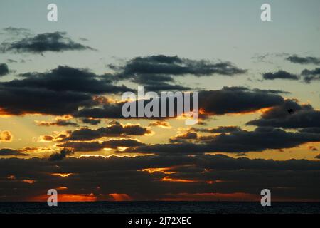 Il sole sorge sull'oceano e attraverso le nuvole Foto Stock