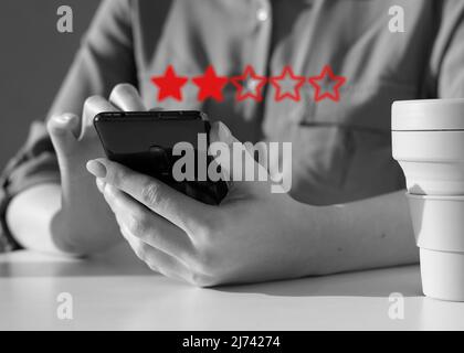 Due stelle. Donna che dà feedback negativo al telefono. Valutazione della qualità del servizio, dell'applicazione smartphone o del prodotto. Cattiva esperienza del cliente. Insoddisfazione del cliente. Foto di alta qualità Foto Stock