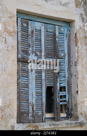 Persiane blu pallido intemperie sulla finestra di un edificio dilatato Foto Stock