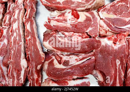 Vista dall'alto di pezzi di manzo fresco con grasso che giacciono sul bancone al mercato del villaggio. Foto Stock