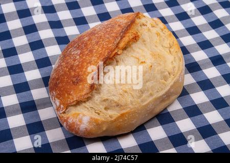 Pagnotta intera di pane di scoring appena sfornato su sfondo bianco blu a scacchi Foto Stock