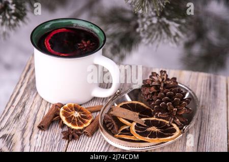 Primo piano di tazze con VIN brulé e spezie su un tavolo di legno in inverno. Bevanda calda invernale Foto Stock