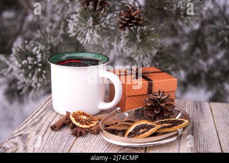 Tazza bianca in ceramica con scatola regalo VIN brulé e spezie su un tavolo in legno in inverno. Bevanda calda invernale Foto Stock