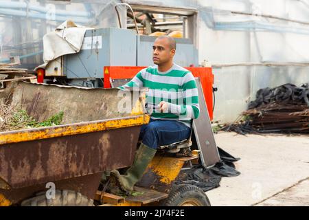 Contadino latino-americano che guida un mini camion, prende fuori per buttare fuori le erbacce. Foto Stock