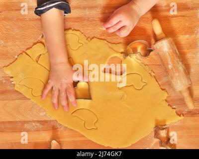 la foto mostra una vista dall'alto di una mano di un bambino piccolo che usa la taglierina per biscotti Foto Stock