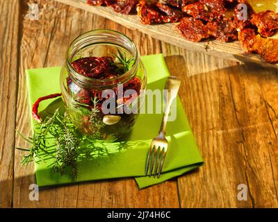 pomodori secchi in vaso; il sole del mattino illumina la situazione, pomodori secchi su bianco legno sullo sfondo Foto Stock