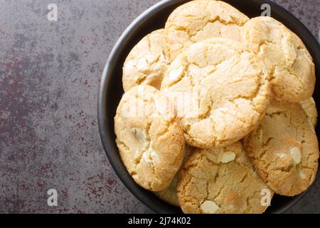 Biscotti al cioccolato bianco e noci di macadamia nel piatto sul tavolo primo piano. Vista dall'alto orizzontale Foto Stock