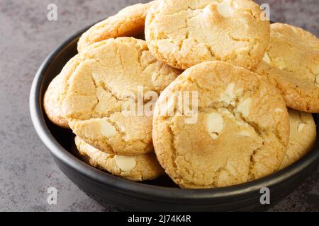 Biscotti al cioccolato bianco e noci di macadamia nel piatto sul tavolo primo piano. Orizzontale Foto Stock