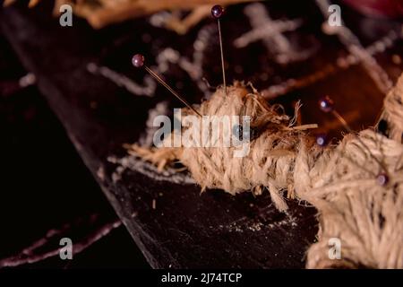 Concetto di Voodoo Magic. Bambola Voodoo costellata di aghi con cuore di straccio trafitto sul pentagramma e intorno a candele brucianti. Spooky o misterioso magico Foto Stock