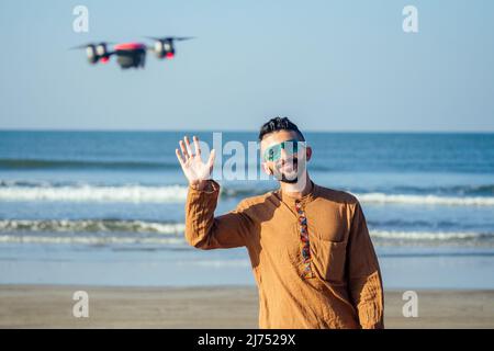 Telecomando drone. L'uomo arabo che opera il controller copter senza contatto con le mani dal mare Foto Stock