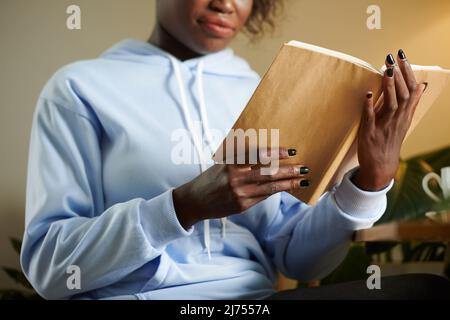 Immagine ritagliata dello studente universitario in libro di lettura con cappuccio blu chiaro per la classe Foto Stock