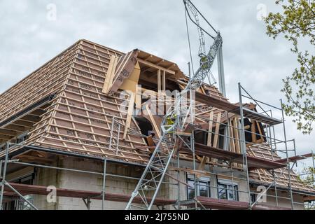 la gru da costruzione piegata cadde nella capriata del tetto appena eretta Foto Stock