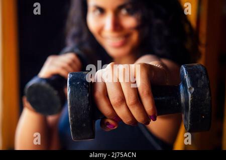 hispanic latino riccioli capelli american donna facendo colpo diretto con manubri Foto Stock