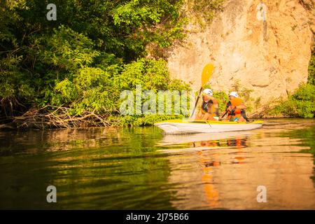 La coppia sta facendo kayak insieme mentre va verso i kayak che si riuniscono nel mezzo del fiume Foto Stock
