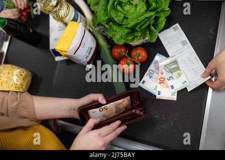 Primo piano della donna che dà denaro al banco cassa del supermercato Foto Stock