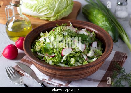 Insalata con cavolo cinese, cetrioli, ravanelli e erba cipollina, condita con olio d'oliva Foto Stock