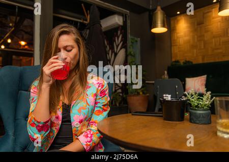 Bella e bella signora giovane sta bevendo il suo cocktail Foto Stock