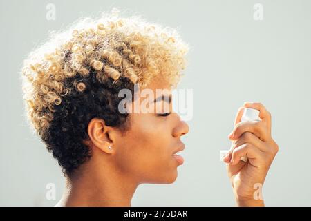 donna americana in africa che usa l'inalatore di asma nello studio sfondo bianco Foto Stock