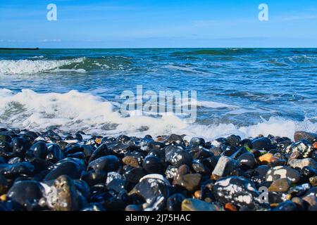 sulla spiaggia del mar baltico con molte pietre e onde che ondeggiano sulla spiaggia. Paesaggio naturale girato Foto Stock