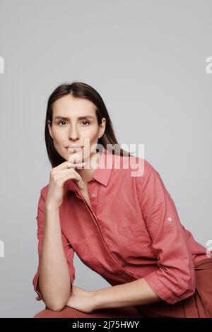 Ritratto di contenuto giovane donna fiduciosa in blusa rosa testa appoggiata a mano su sfondo bianco Foto Stock