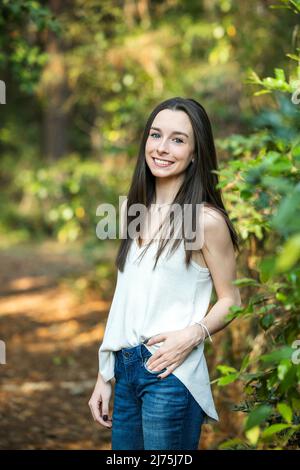 Una bella ragazza bruna adolescente felice all'aperto in una zona boscosa in primavera Foto Stock