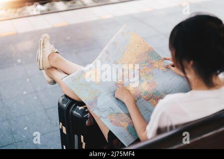 Lato posteriore della ragazza del viaggiatore che cerca la giusta direzione sulla mappa, viaggiando lungo asiatico in treno, libertà e stile di vita attivo concetto Foto Stock